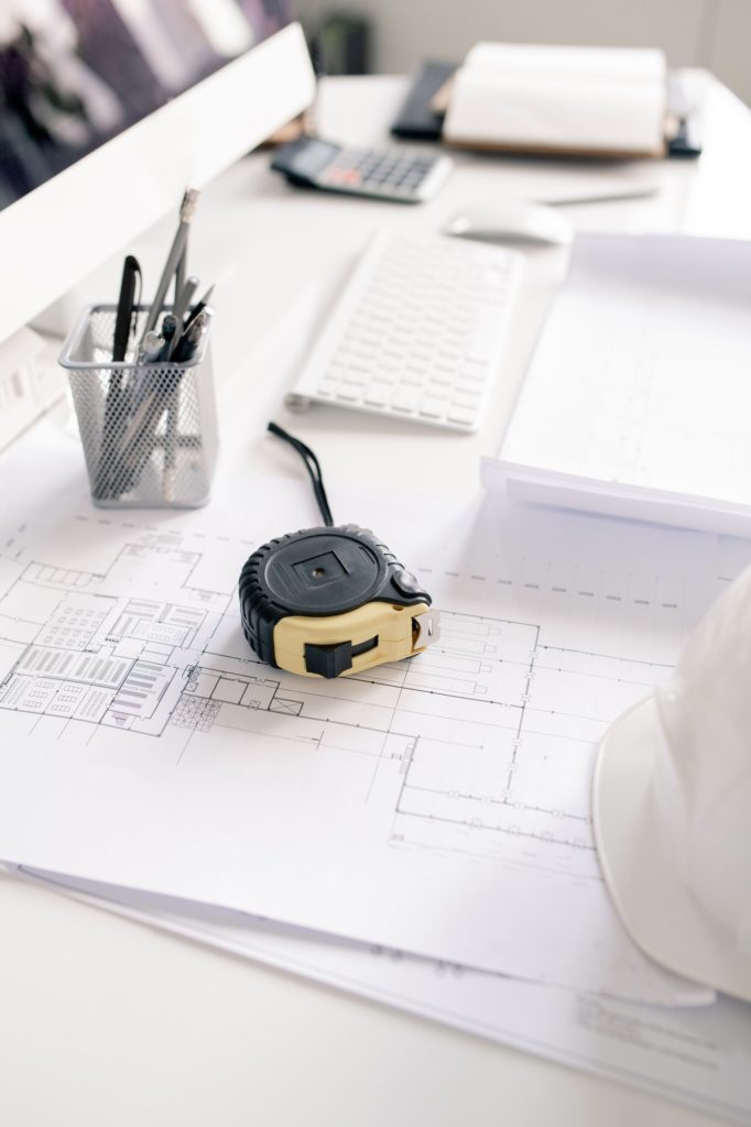 Measuring tape, pencils and blueprints with sketches on workplace of engineer